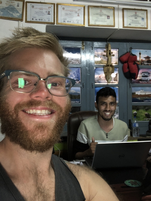 Two people indoors with various travel posters.