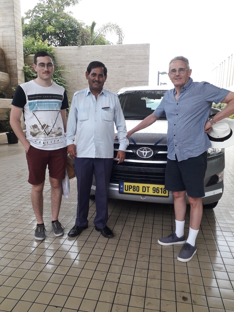       Three men posing in front of a vehicle
  
