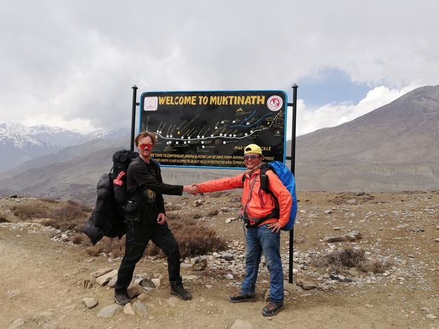      Two hikers shaking hands in front of a sign
  