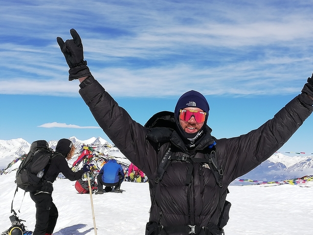       Hikers celebrating on a snowy mountain with prayer flags
  