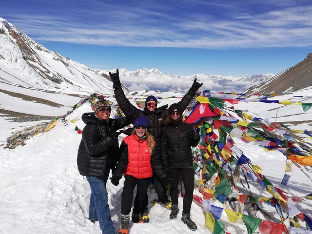       Group of people celebrating in a snowy mountain with prayer flags
  