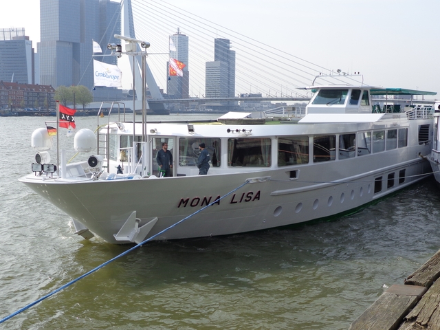 Boat named Mona Lisa docked near the Erasmus Bridge with people onboard.