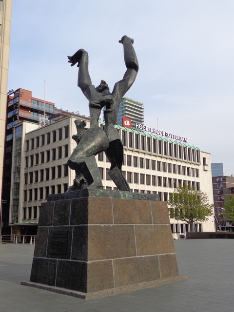 Bronze statue in front of a Rotterdam building with modern architecture.