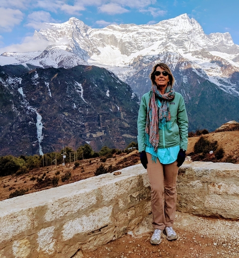Person standing with mountains in the background wearing a scarf.