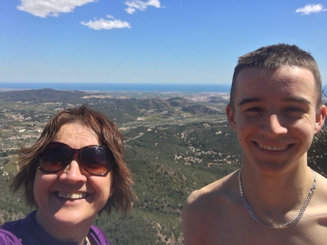       Two people smiling with a hilly landscape in the background.
  