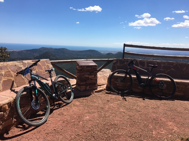 Two bikes parked at a scenic viewpoint overlooking the sea.