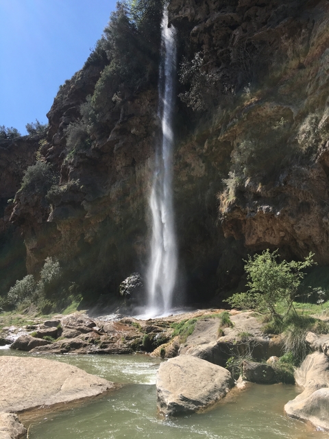       Waterfall flowing down a tall rocky canyon.
  