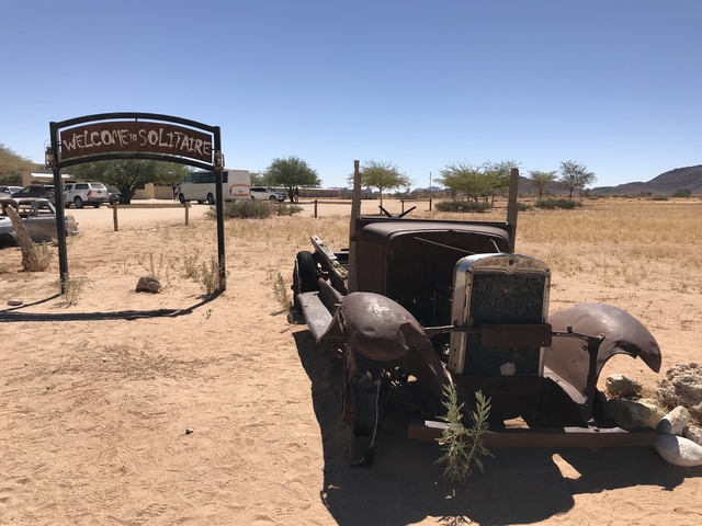       Rustic car in front of a 'Welcome to Solitaire' sign.
  