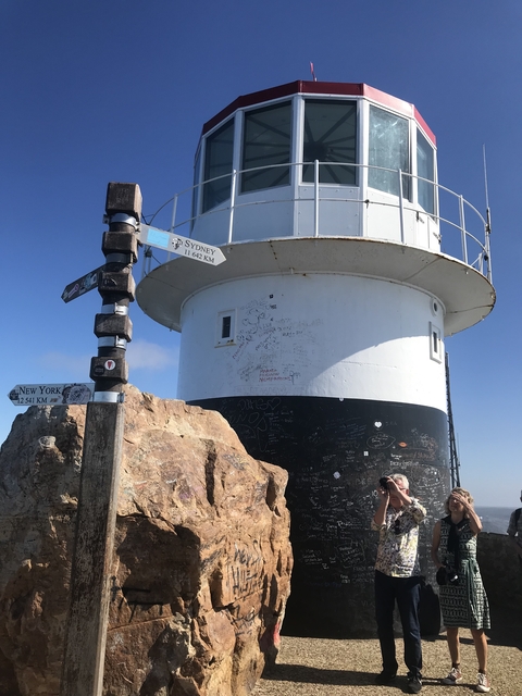 Person standing in front of a lighthouse with distance signs.