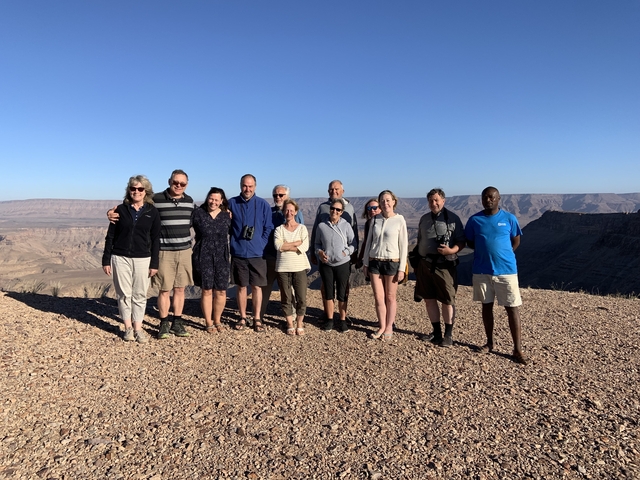       Group of people posing at a canyon viewpoint.
  
