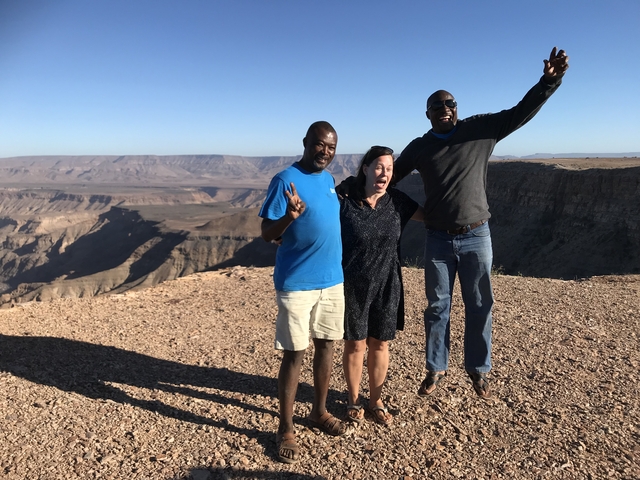       People posing at a canyon viewpoint.
  