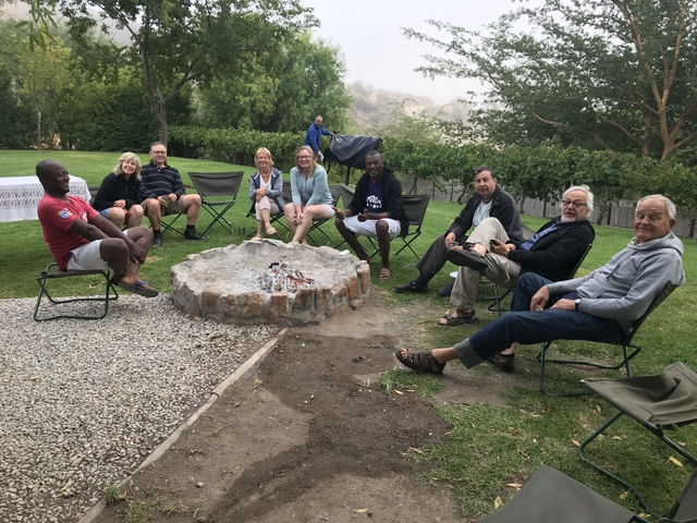       Group seated around a campfire outdoors.
  