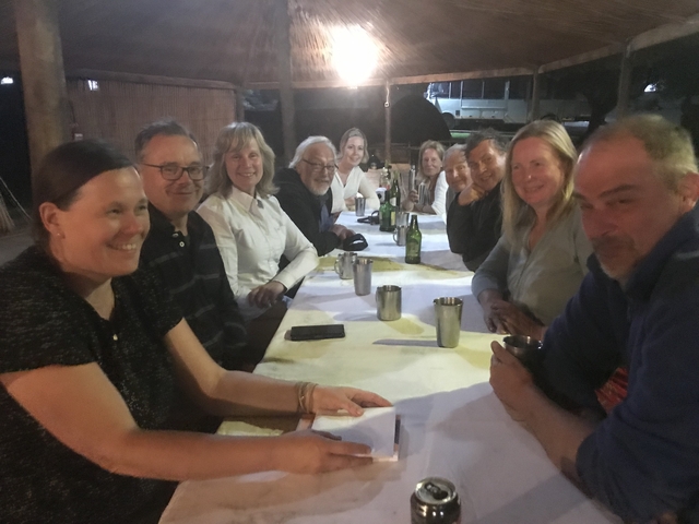       Group of people sitting at a dinner table outdoors at night.
  