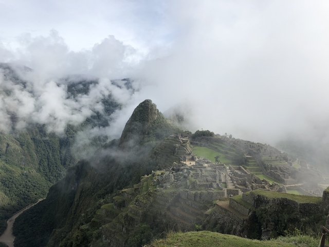 Machu Picchu in the mist with mountains in the background.