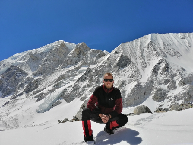 Person in a snowy mountainous landscape, posing in front of rugged mountains.