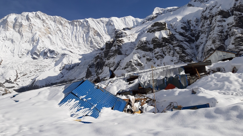 Snow-covered mountain landscape with blue corrugated metal structures.