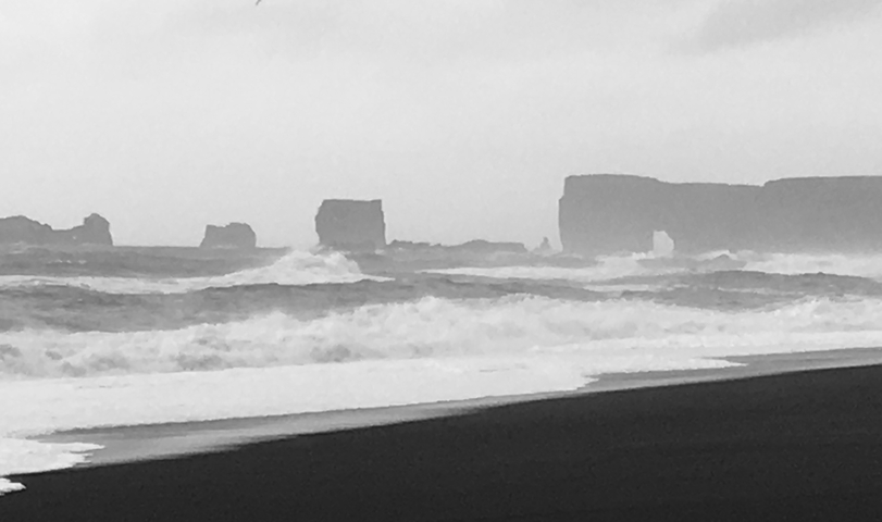       Black and white image of rocky sea stacks.
  