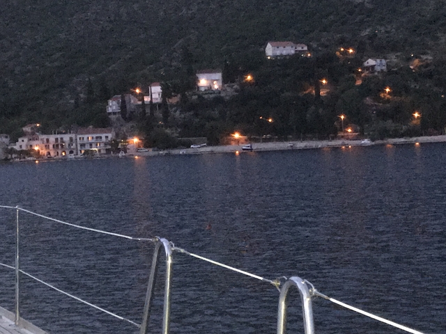       Night view of a coastline with lights reflecting on the water.
  