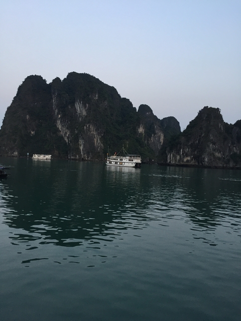       Boats on a calm sea with large rock formations.
  
