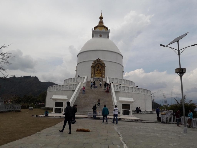White stupa with a golden spire on a hilltop.