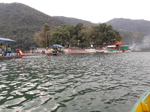 A lake with boating activity surrounded by hills.