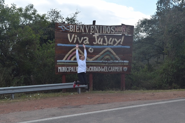Jumping person in front of a sign saying 'Viva Jujuy'.