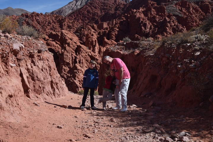 Family of three posing in a red rock canyon.