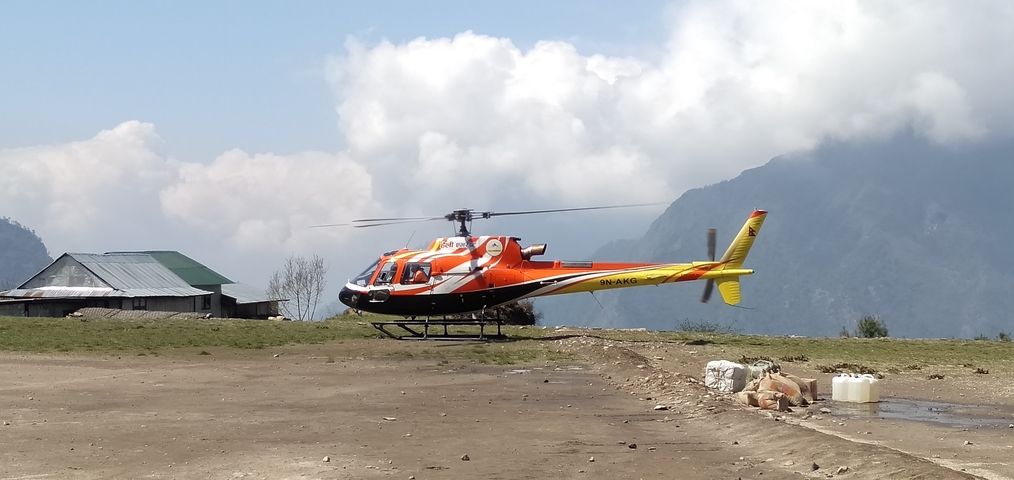 Helicopter parked on a mountain airstrip with mountains in the background.