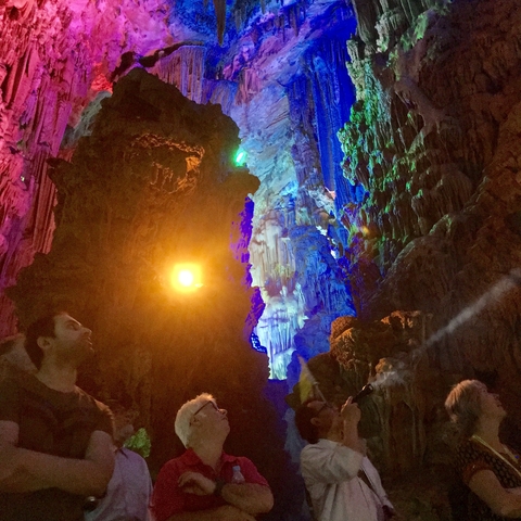 Colorfully lit cave interior with people observing.