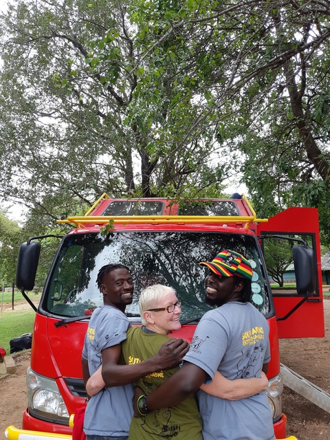       Three people smiling in front of a red fire truck.
  