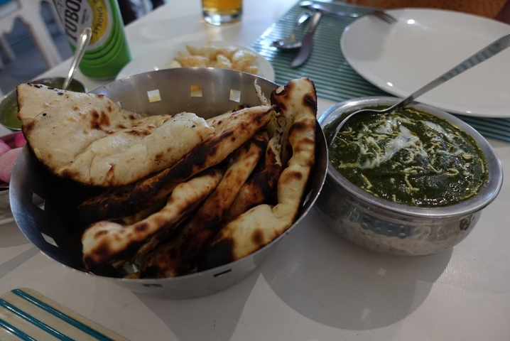       Basket of naan bread with a side of palak paneer.
  