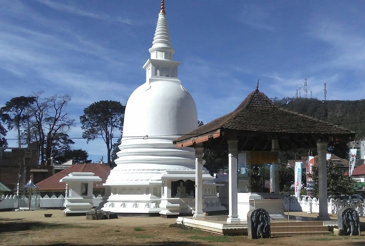 A white stupa surrounded by a few structures.