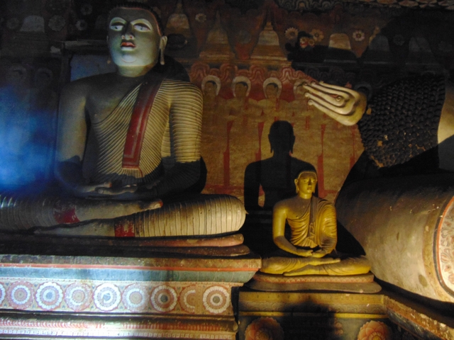 A dimly lit cave with statues of Buddha.