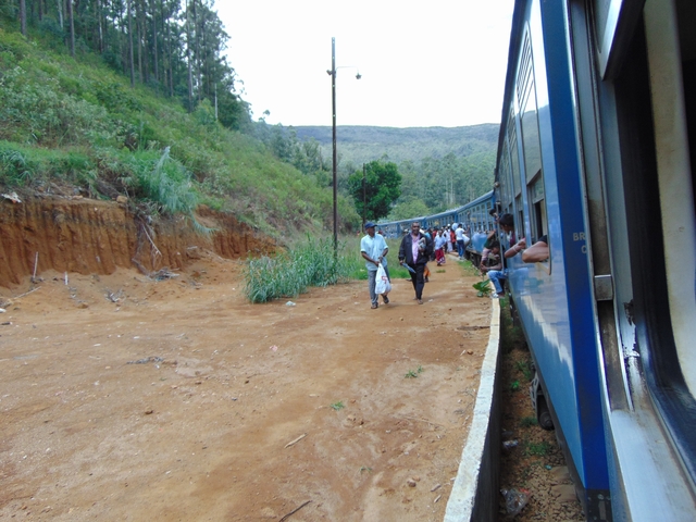 People boarding a train in a rural landscape.