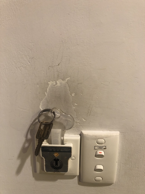 Keyring hanging from a wall with peeling paint.