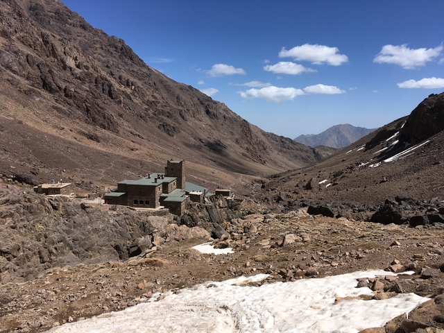 Valley with a building nestled between mountain ranges.