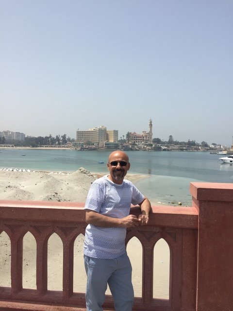 A man standing in front of a waterfront cityscape.