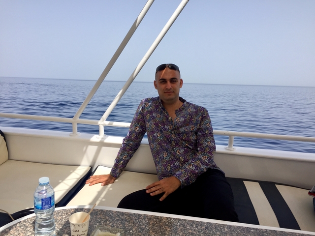 A man sitting on a boat in open water.