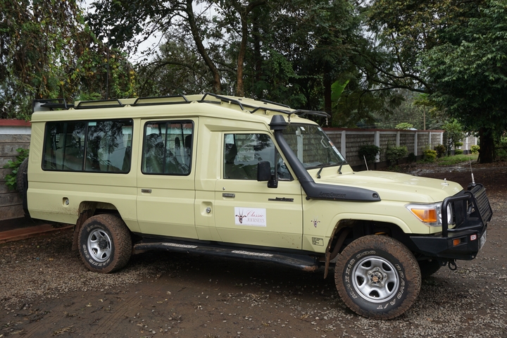       A safari vehicle parked on a dirt road.
  