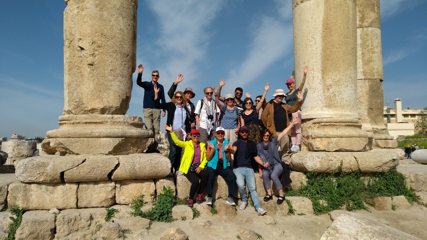 Large group of people posing in front of ancient ruins.