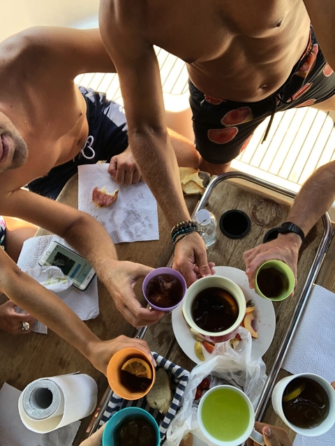       People enjoying a meal with drinks on a boat table.
  