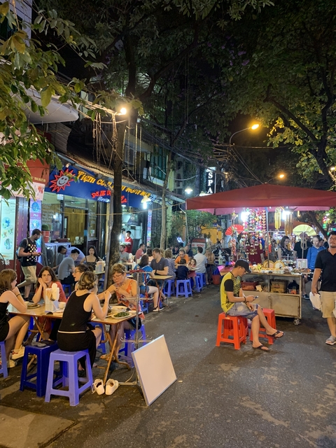 Street market scene with people dining outdoors at night.