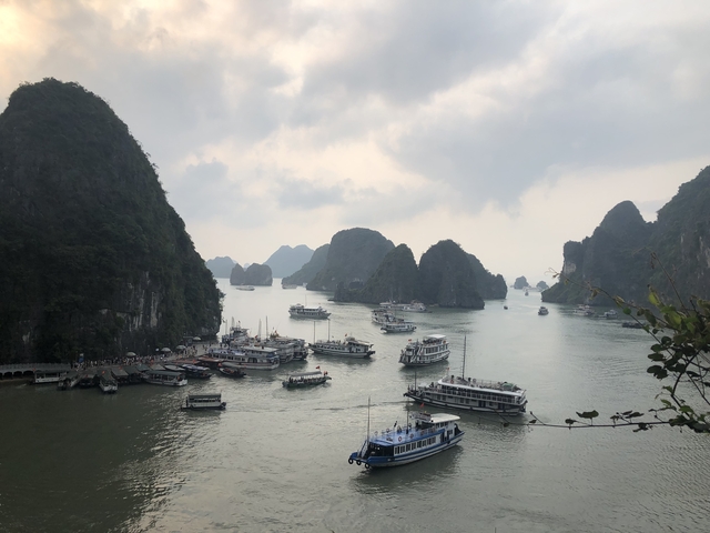 Numerous boats on the water with limestone karsts landscape.