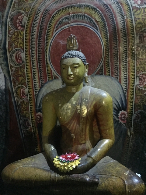 Buddha statue indoors with a colorful backdrop.