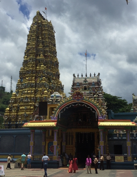 Colorful temple with intricate carvings and cloudy sky.
