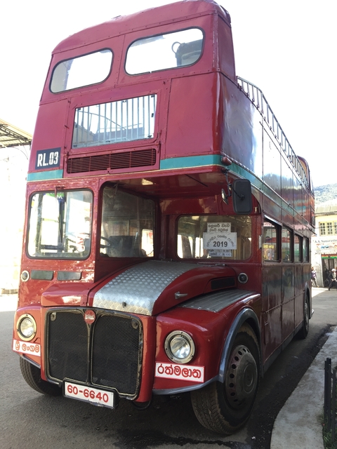 Red vintage double-decker bus in a city.