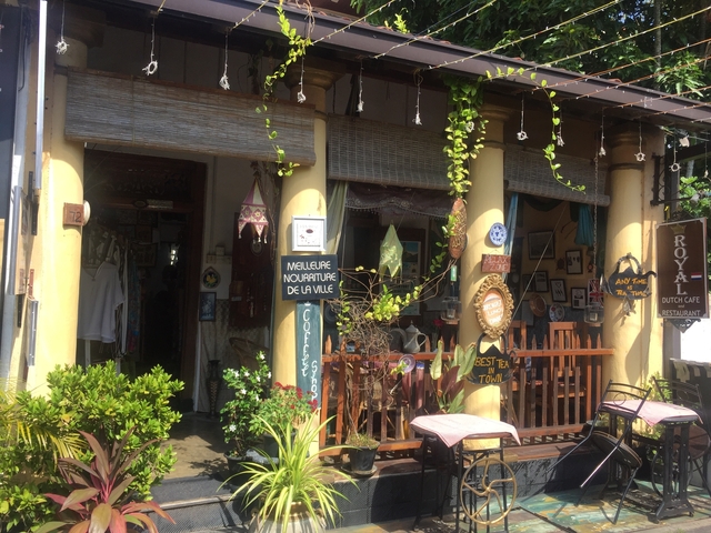 A cozy cafe entrance with decorative signs and greenery around.