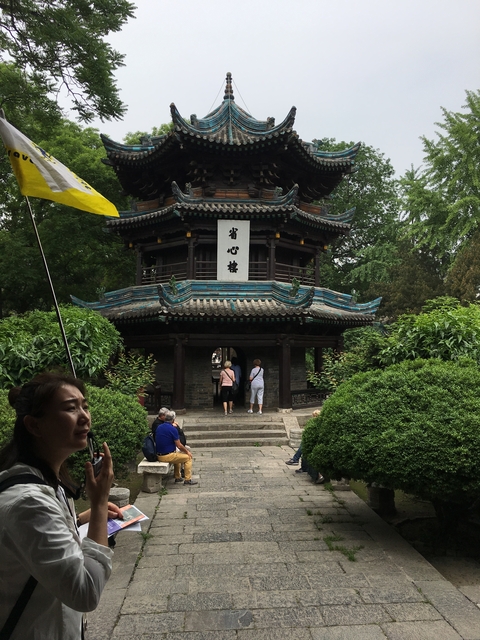       Tourists in front of a traditional pagoda with lush greenery.
  
