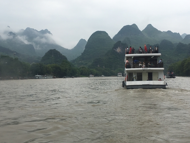       Tourists on a boat cruise with karst mountains in the background.
  
