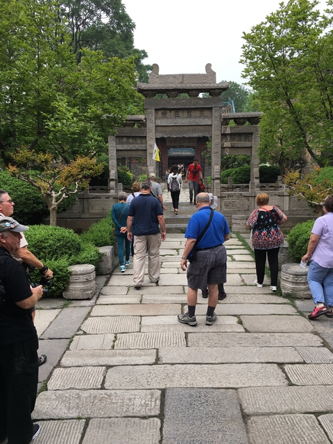       Tourists walking towards a traditional Chinese structure.
  